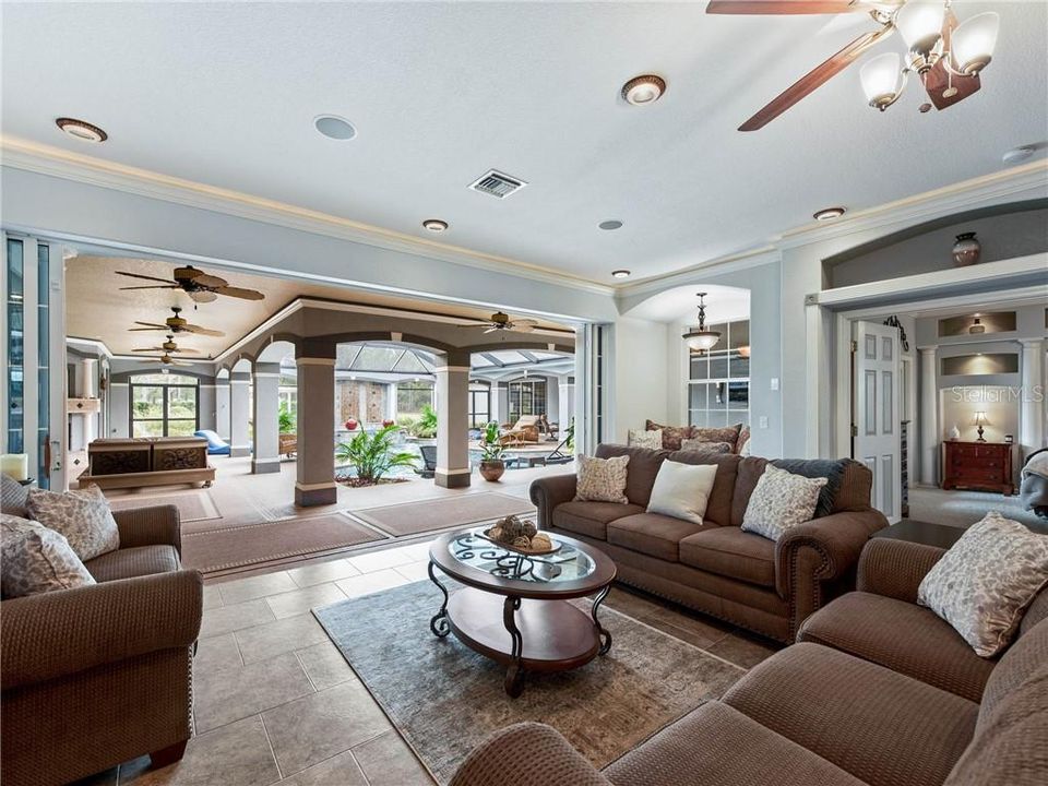 Stunning views of your backyard Tropical Oasis from the Great Room. The 18' of sliding glass doors pocket back into the wall behind the decorative columns bringing the outdoors in. The arched niche is the perfect place to rest where the window seat with storage is nestled in the corner below the pendant light. The Owner's Suite is to the right through the double French doors.