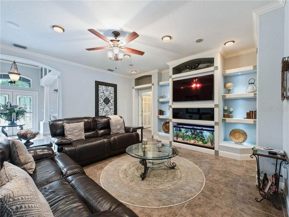 Relax with your family and friends in this comfortable family room with a full media built-in with fish aquarium, crown molding, recess lighting with decorative trim and ceiling speakers.