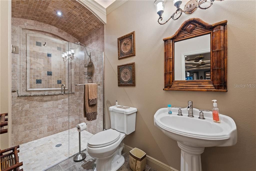 Private Pool Bathroom accessed from the Covered Lanai with a Beautiful shower (no threshold), arched shampoo niche, frameless glass doors, bamboo style faucet fixtures, crown molding with ambient rope lighting, pedestal with accent mirror and lighting.