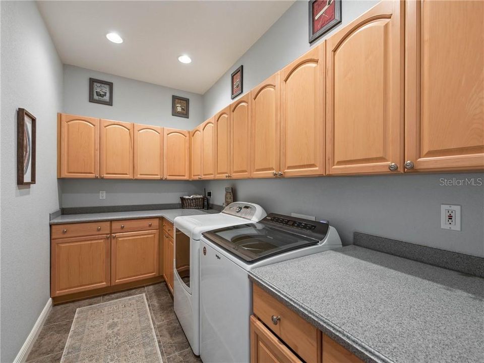 FABALOUS Laundry room fully equipped with washer, dryer, custom-made roll-out laundry hamper, base cabinetry with 30" upper cabinets, nickel hardware, DuPont Corian countertops with an ogee edge and recess lights.