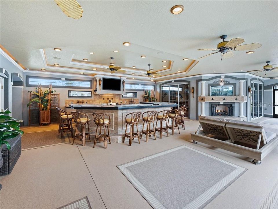 Covered Lanai with tray ceiling fans, recess lighting with decorative trim, crown molding, Outdoor Kitchen and Billiard and Game Room with the Built-in gas fireplace with the 2-sided fish aquarium and Queen size day bed on casters.