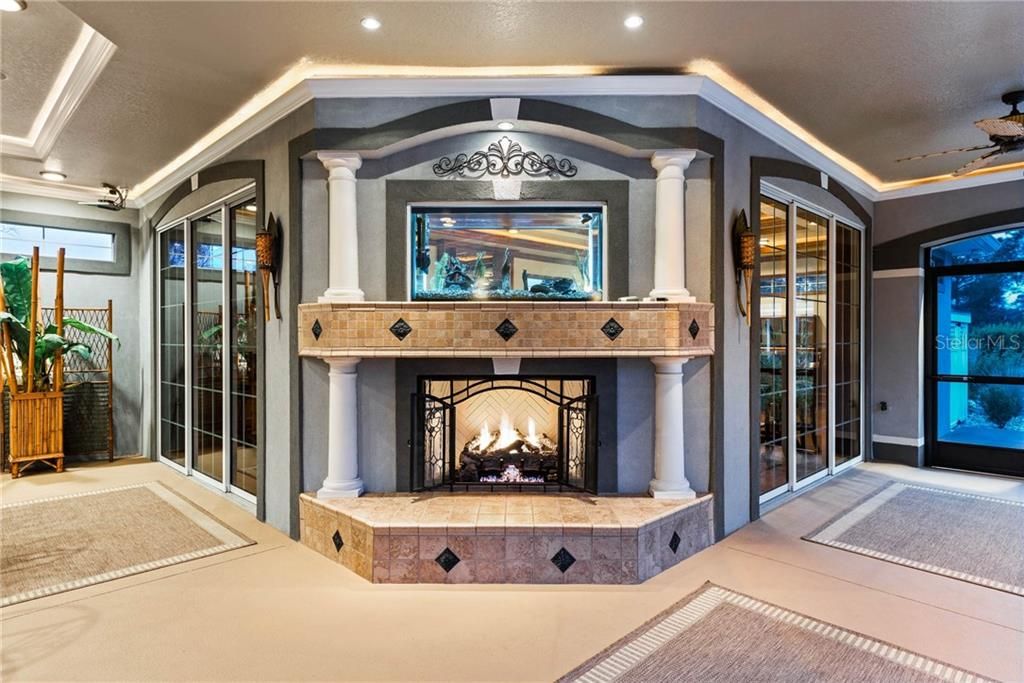 Evening view of the gas fireplace with the 2-sided fish aquarium. The state-of-the-art Billiard and Game room may be completely opened up with the two sets of sliding glass doors.