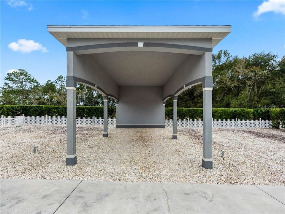 15' x 32' RV Port with 12'-2" clearance. There are 3-30 amp hookups, 5 water spigots and additional weather proof GFI outlets. Just beyond in the left corner, there is a 500 gallon buried propane gas tank that services the gas Hibachi grill, spa and fireplace at your Tropical Oasis!