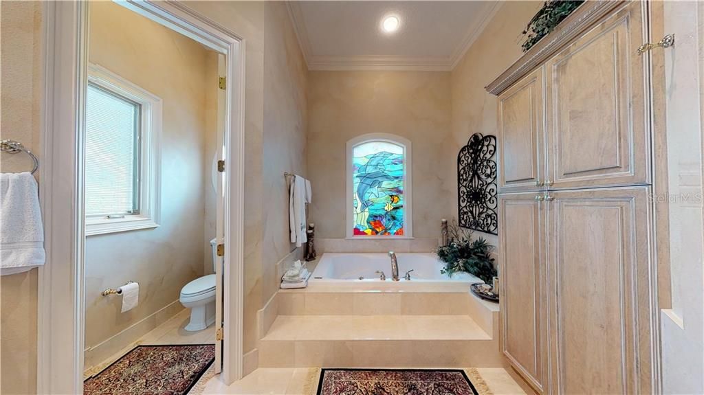 En-suite bath with large jetted tub, custom linen/storage closet, private toilet room, his/her sink, vanity, separate shower.