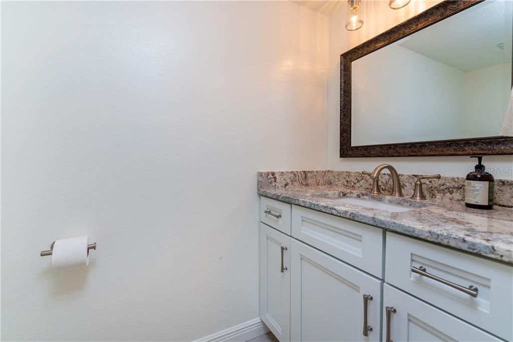 Half bath on ground floor opposite kitchen has been beautifully updated with solid wood vanity and granite counter