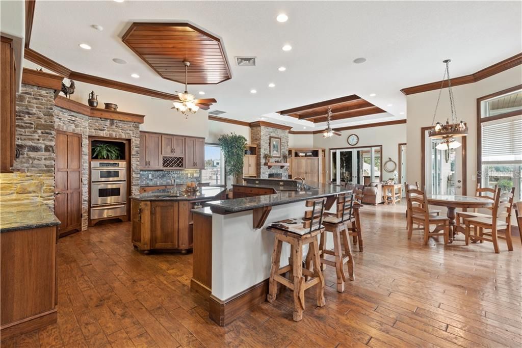 Gourmet STONE KITCHEN with Island Cooktop, convection oven, eat-in space, walk in pantry, and breakfast Bar.