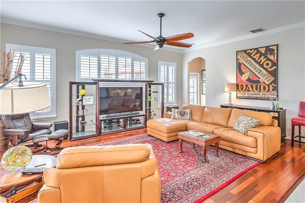 The family room features Plantation Shutters, wood floors, Crown molding & an upgraded ceiling fan!
