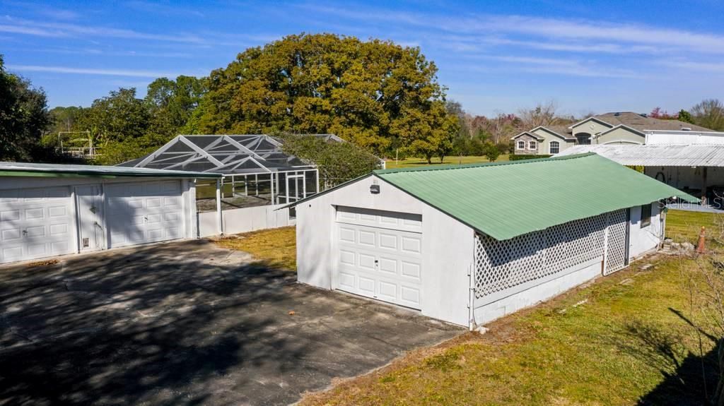 Building Structure 2 with another garage (that would be storage for the 5th vehicle if you are counting); behind it is a taller shed with 15 foot ceilings and 28 feet deep - great for long bed trucks, campers/RV's and boats! Additional covered parking on both sides fr mowers or trailers too.