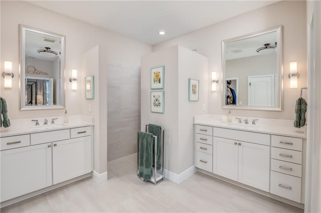 Master Bath has double sinks, custom vanity mirrors and sconce lighting, porcelain tile floors and walk in shower.