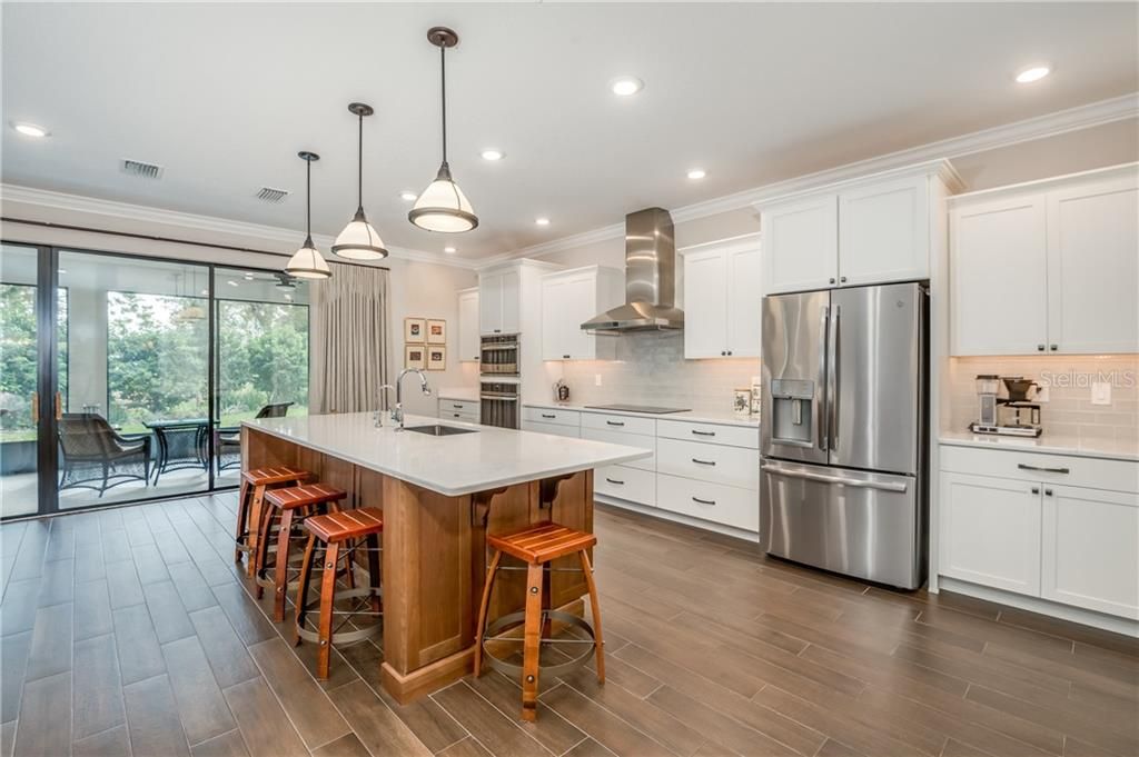 This custom kitchen has a cherry wood island with quartz counter tops, stainless steel appliances, an induction cooktop stove, convection oven & microwave. It is a chef's dream kitchen.
