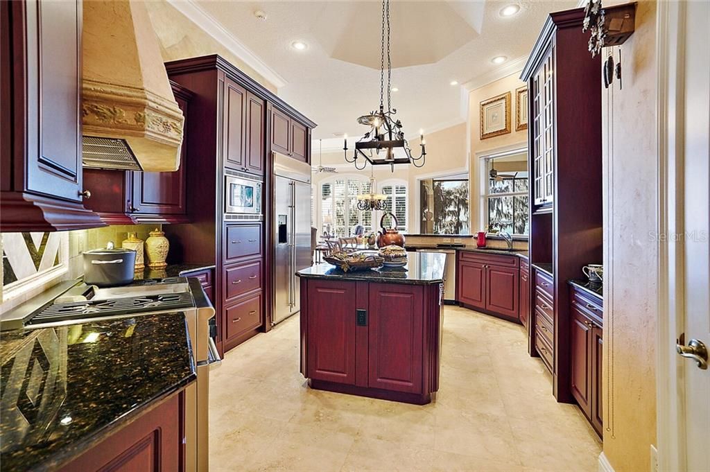 The well-appointed kitchen is complete with custom wood cabinetry, granite counters, commercial-grade appliances, including a gas range, prep island with storage and extra sink, pass-thru window to lanai, amazing Butler???s pantry with sink and wine refrigerator.