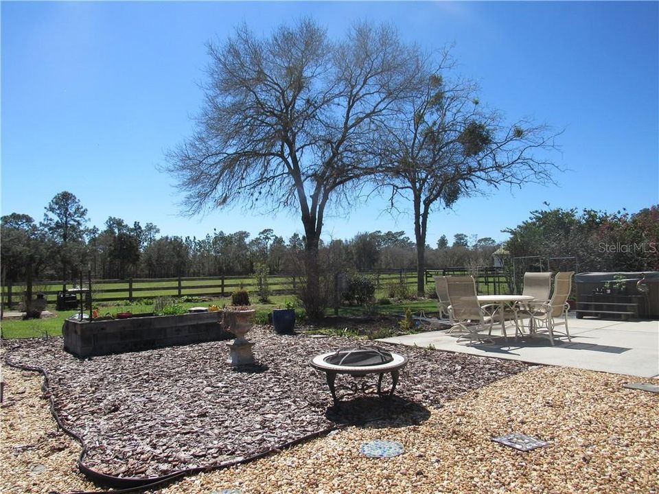 What a great area right outside your kitchen!  Enjoy a fire in the evening while sitting in your hot tub or have a nice light dinner while watching your horses run and play.  Raised garden beds will keep you busy and with food all year round.