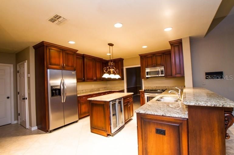 From Breakfast Area - you can see the WALK IN PANTRY and Laundry Room Door, STAINLESS APPLIANCES including Convection Cooking, Wine Fridge as well as bar seating.