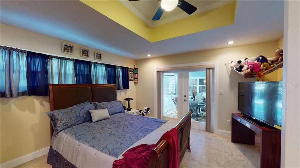 Bedroom #4 - tray ceiling, ceiling fan and french doors to the massive screened enclosure.