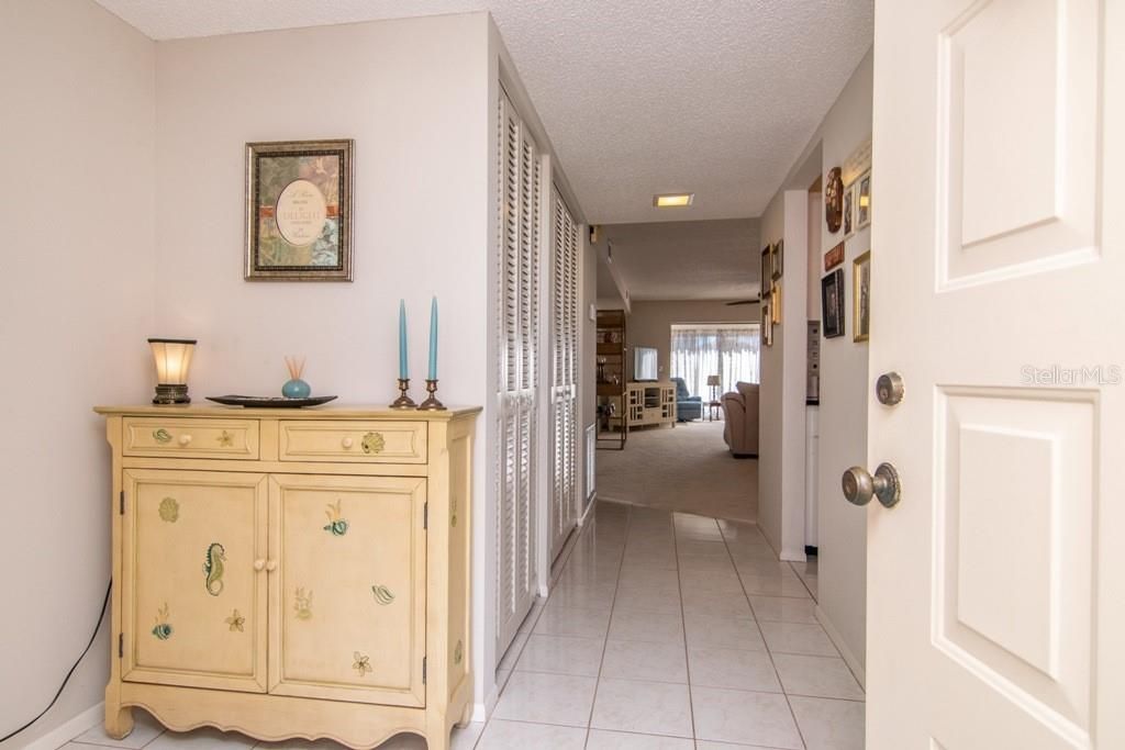 Front entry hallway with large white tile leads you directly to the kitchen on R and living and dining area just beyond.