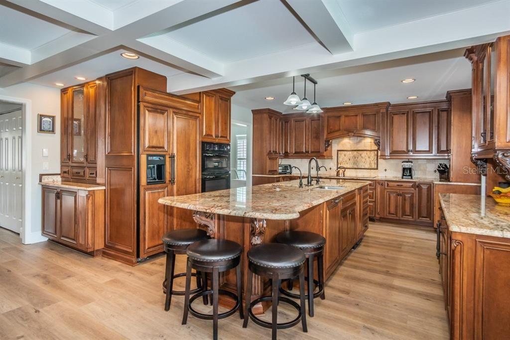 Kitchen with large island counter, built-in appliances and expansive storage.