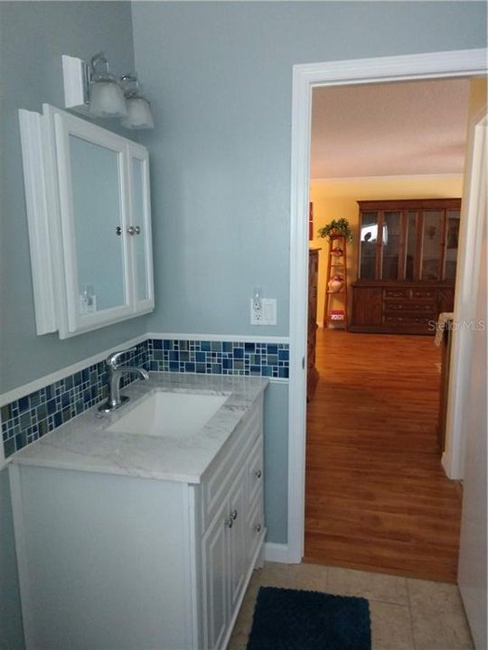 Updated main bath features exquisite tilework, vanity w/marble top, medicine chest and new light.