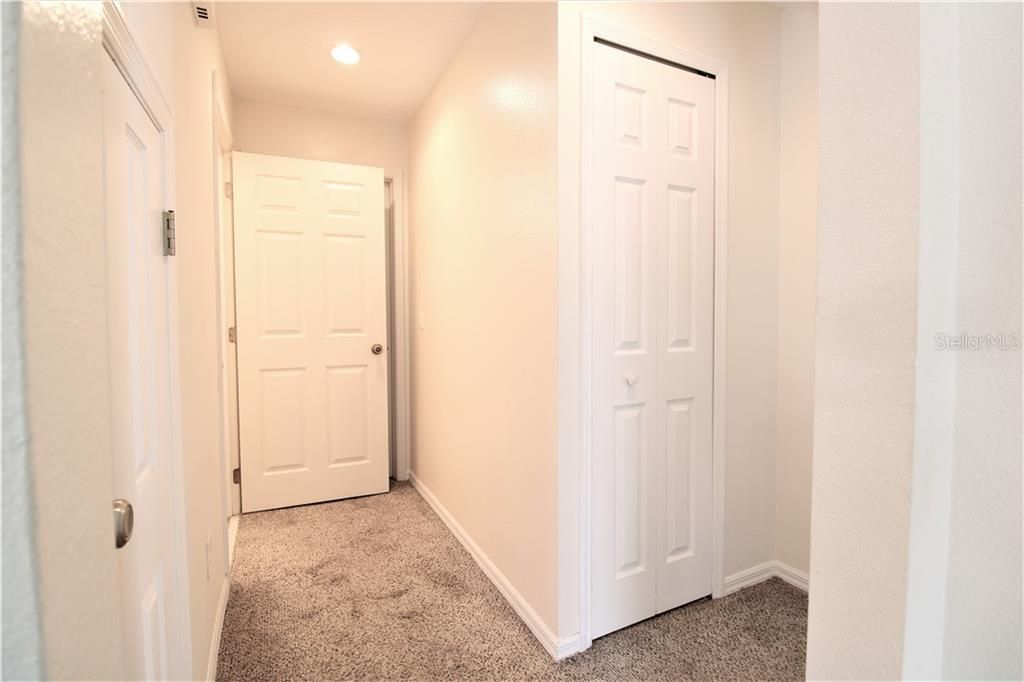 Side hallway with half bathroom (to the left), garage entrance (straight ahead) and master bedroom entrance (to the right)