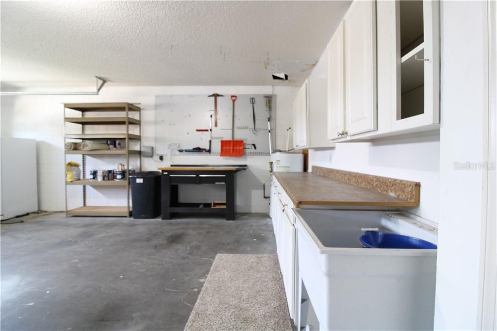 Garage features shelving space, cabinets and sink