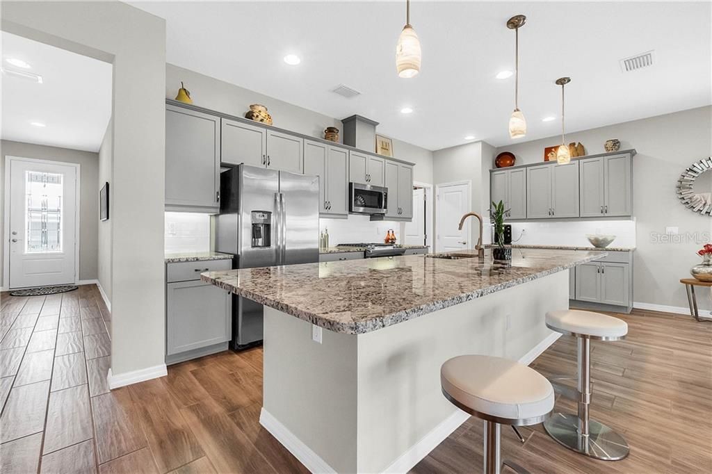 Graced with granite countertops, matching stainless steel appliances , GAS range, tiled backsplash, upgraded cabinets and pendant lighting