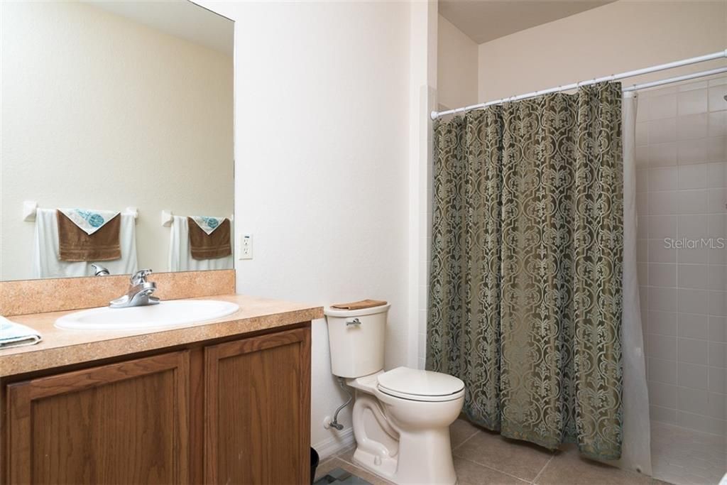The master bathroom as a comfort height stool and large stall shower with ceramic tile surround.