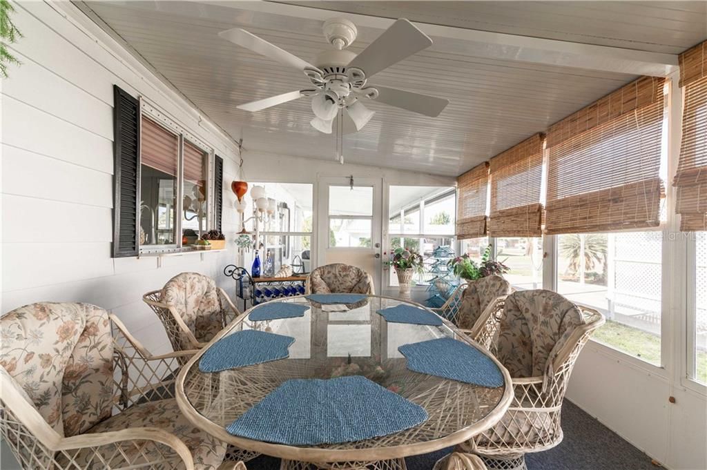 This furnished home has carpeting and ceiling fan in Florida room.