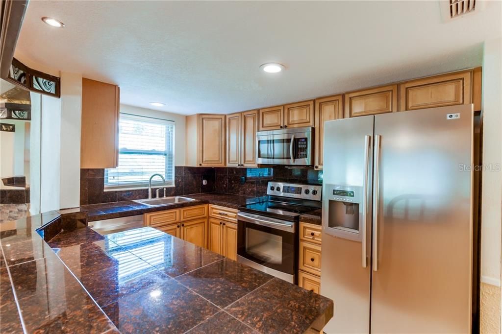 Wonderful kitchen featuring Stainless Steel Appliances, flat surface range, and soft close wooden cabinet drawers