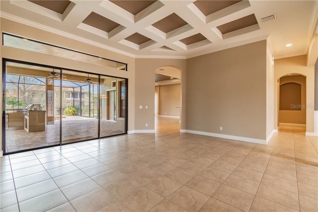 Stunning Coiffured Ceiling Living Room Detailed with Sliding Patio Doors Leading to the  Pool and Lanai