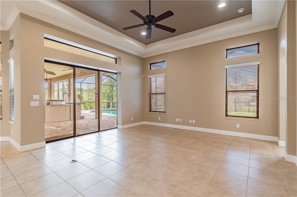 Open Trayed Ceiling Family room With Sliders Leading to the Outdoor Kitchen and Large Lanai.