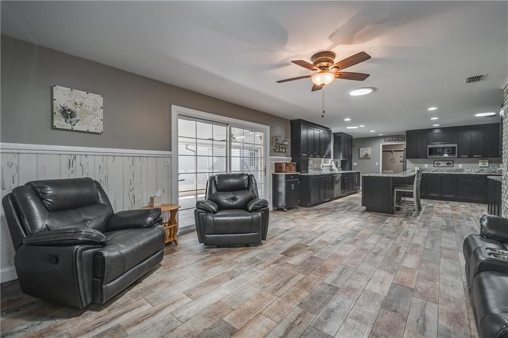 Family Room leading to the Kitchen. Crown Molding, Wall Molding & Trim throughout Pecky Cypress Wainscoting (Wall Panels). New Wood Plank Ceramic Tile throughout entire main house. New Ceiling Fans and Light Fixtures throughout. Double Pane Sliding Glass Door