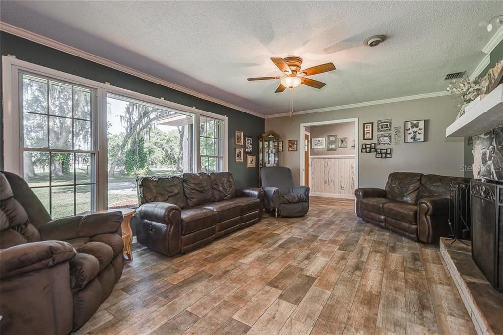 Living Room with Crown Molding. New Wood Plank Ceramic Tile throughout entire main house. New Ceiling Fans and Light Fixtures throughout. Double Pane Windows.