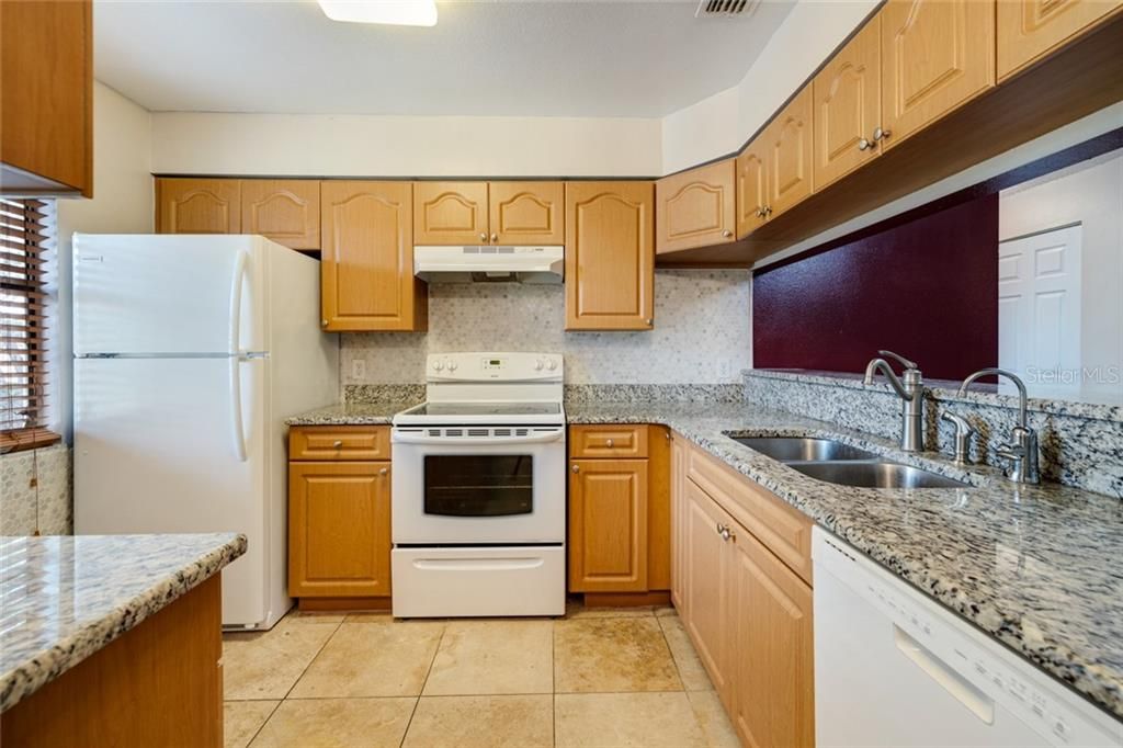 Updated kitchen with quality cabinetry, granite counters, tile backsplash, 18" tile floor