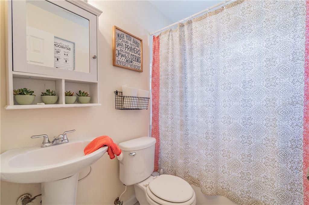 9606 N. Hartts Drive, Tampa, FL 33617 - Bathroom 2 features a tub with shower & pedestal sink.