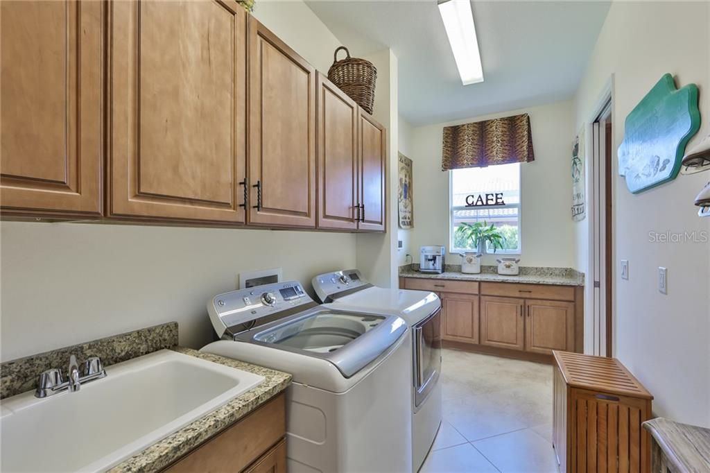 A large utility sink, matching granite counters and a 'coffee bar' makes this space a one of a kind laundry room.