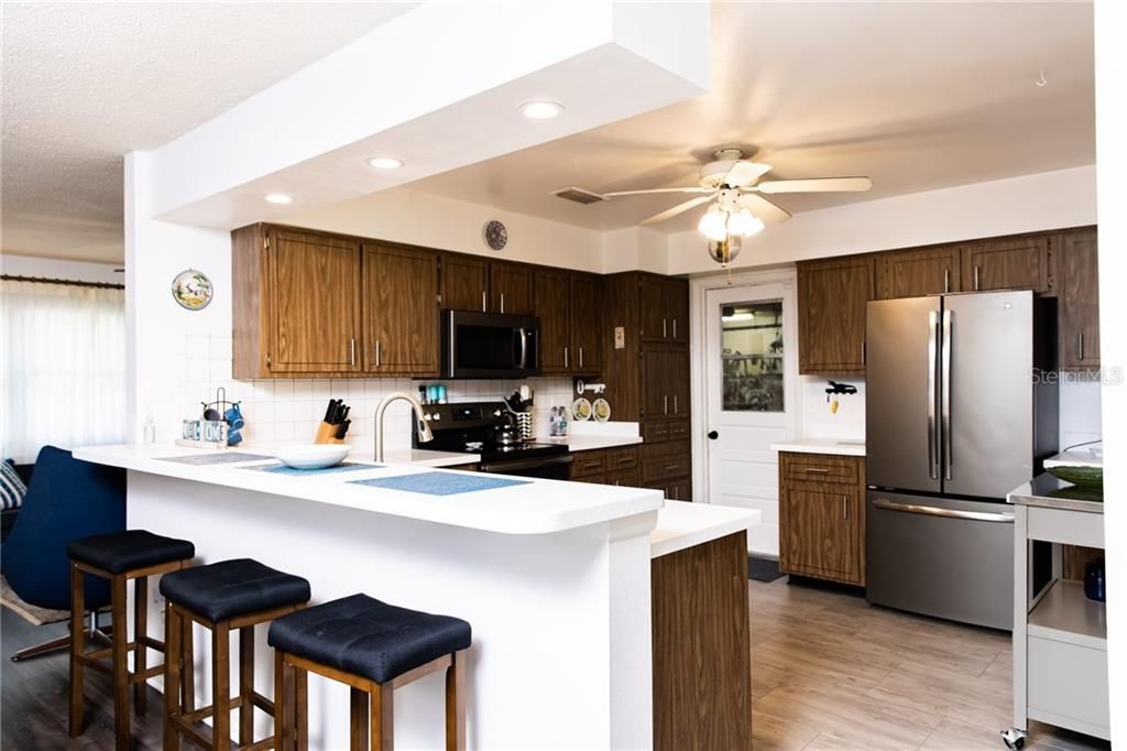Kitchen featuring Breakfast Bar, Newer Stainless Appliances and Corian Counters