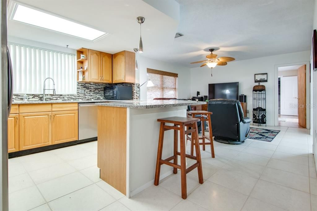 Kitchen with granite counter tops and stainless steel appliances.  High top bar connects to family room