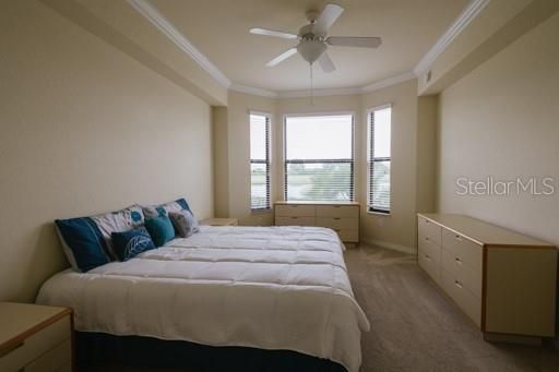 Owners' bedroom with tray ceiling with crown molding and ceiling fan.  And a great view of the lake and golf course.