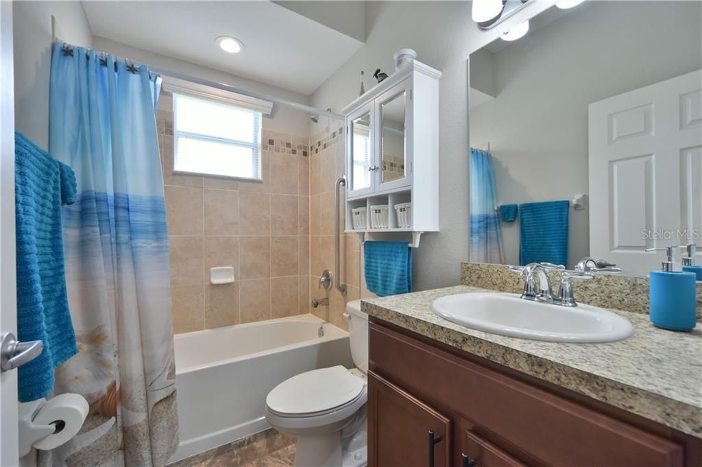 Guest bathroom with natural light from the window and added storage over the toilet.