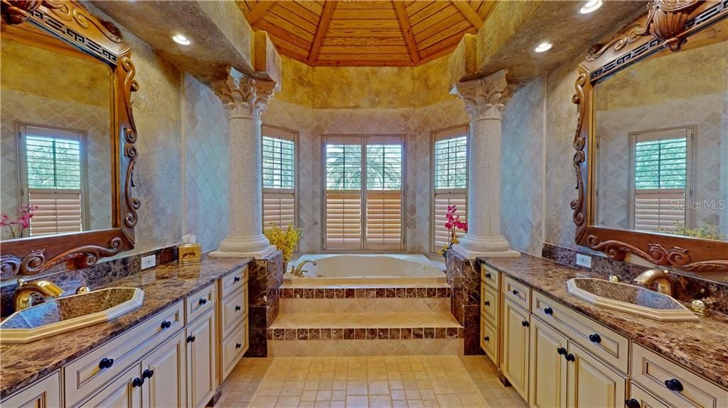First floor master bathroom with matching floor and wall tiles, vaulted wood in-lay ceiling and double vanities.