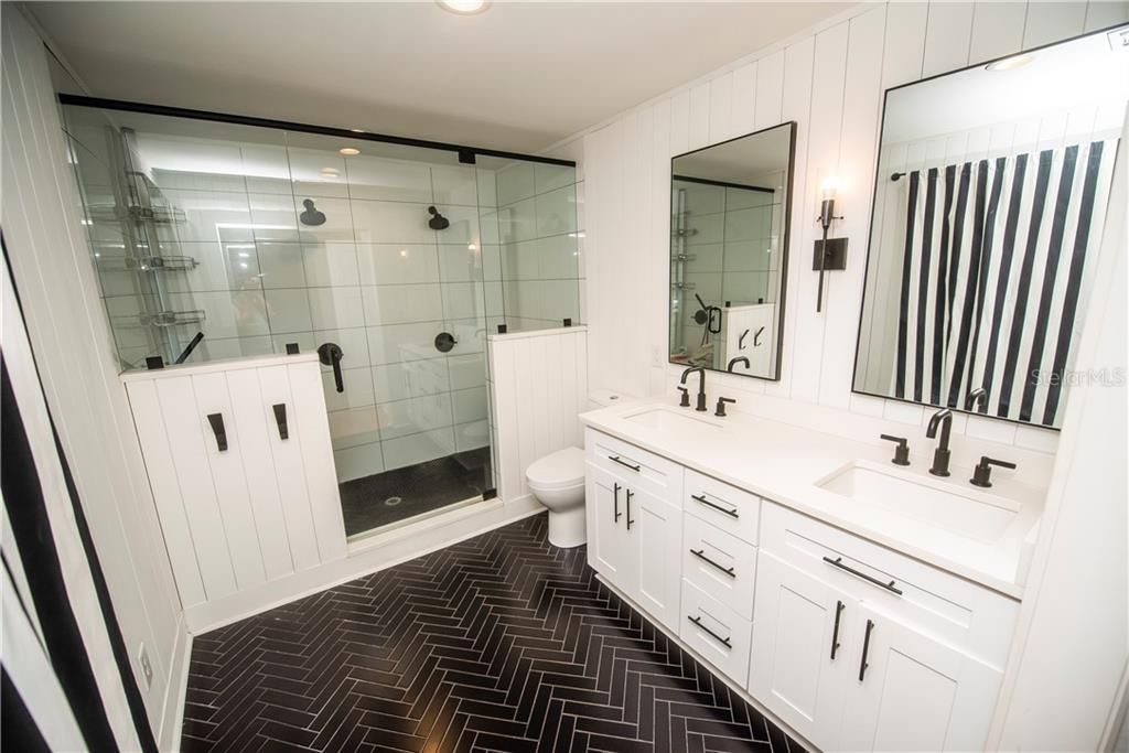 Recently updated master bath features dual showers, dual sink vanity and herringbone tile