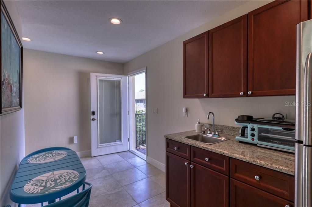 Kitchenette with full refrigerator and sink provides space to eat in the kitchen and another outdoor patio.