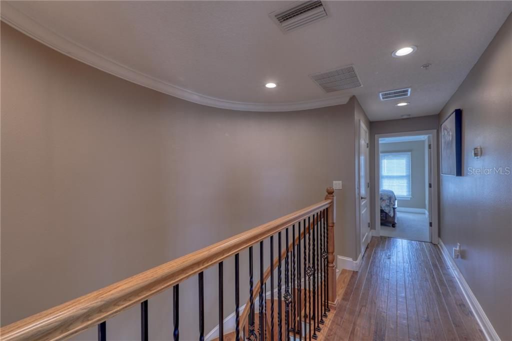 New Hardwood Flooring and Curved Staircase wall. This hallway connects the Master Bedroom and the Second Bedroom which also  has a private on suite bathroom. The craftmanship is beautiful with the rounded wall, wrought iron and wood staircase and crown molding.