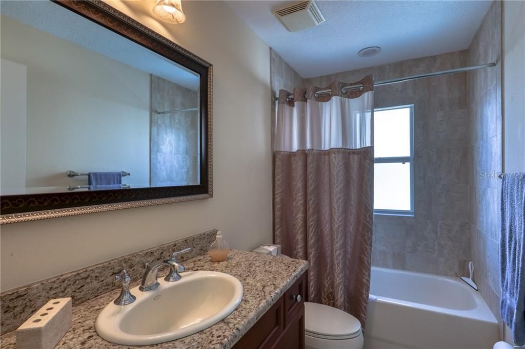 The studio full bathroom with granite counters and tub/shower.