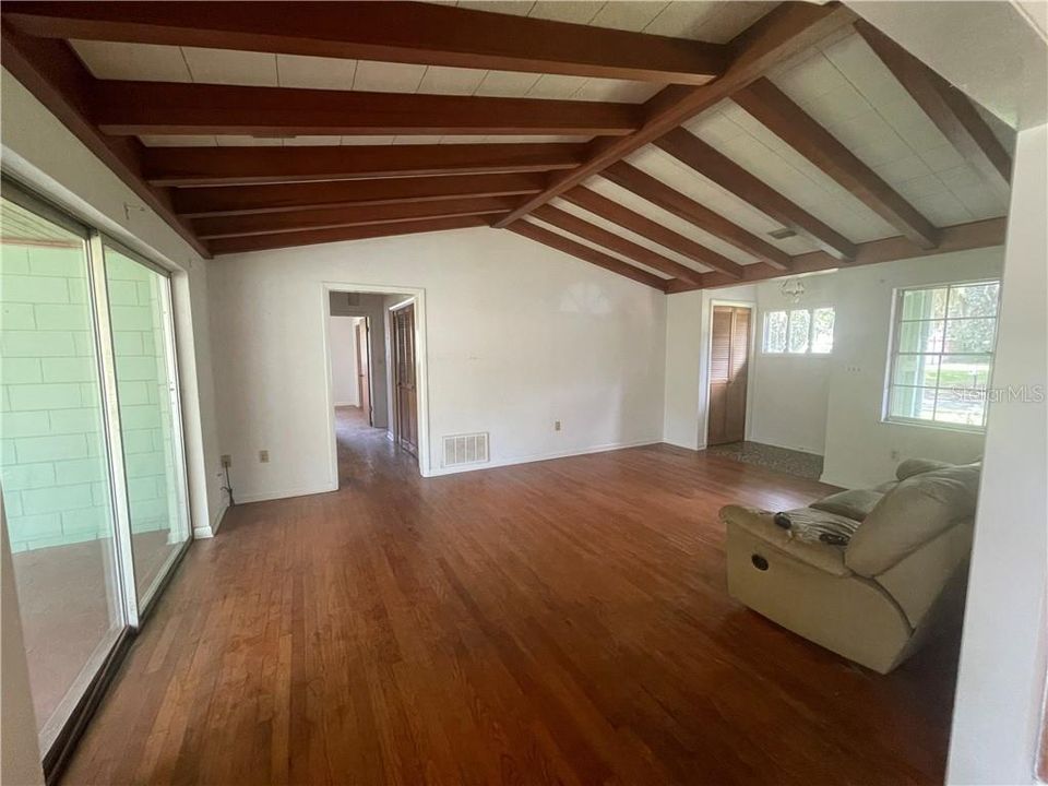 Family Room features hard wood flooring, valued ceiling with wood beams, and sliders leading out to back screened lanai