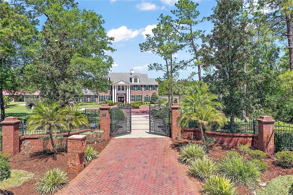 Palatial entrance with gated driveway and brick pavers