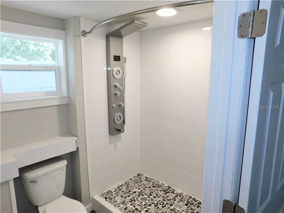 New master bathroom with multi-jet rainfall shower and river rock base