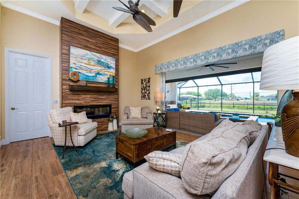 The living room is highlighted by a whimsical dual fan, a decorative ceiling, and expansive sliders that lead to the lanai.