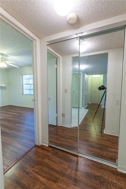 Hallway with mirrored-door to the linen closet.  The 2nd bedroom can be seen to the left of the picture.