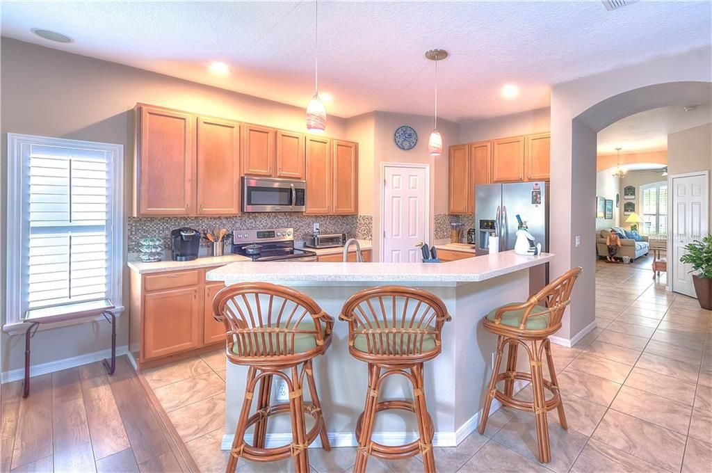 Beautifully appointed kitchen hosts an island, 42: wood cabinets, solid surface counter tops, Stainless Appliances, glass tile backsplash, pendant lights & a walk-in pantry!