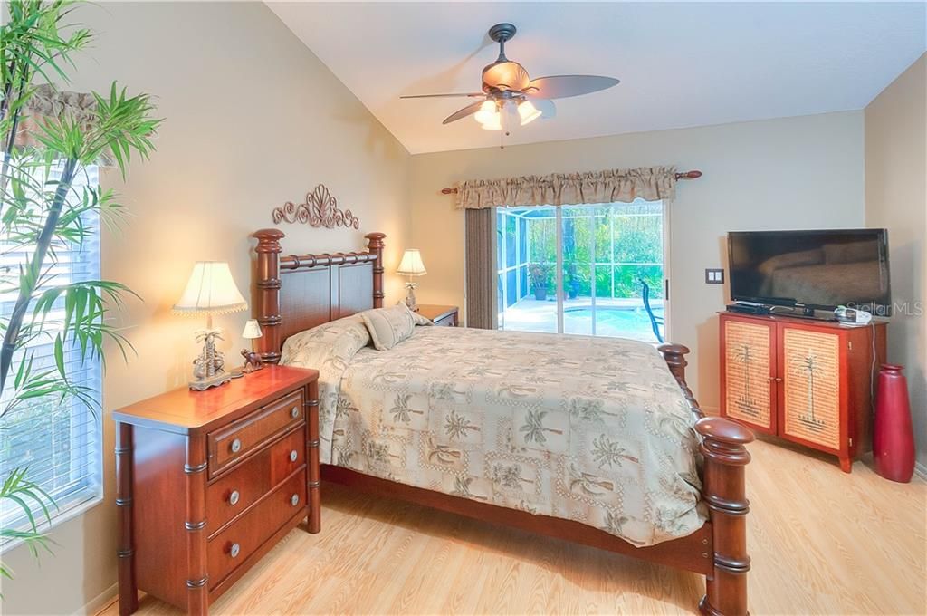 The master bedroom features volume ceilings, ceiling fan, laminate floors, a linen closet & access to the pool & lanai!